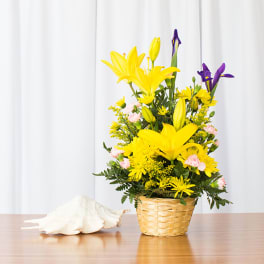Yellow lily and daisy basket arrangement with purple iris and pink accents