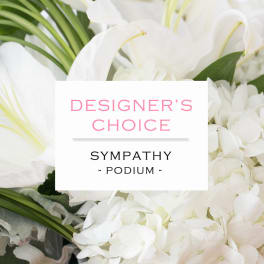 White lilies and hydrangeas with text reading Designer's Choice Sympathy Podium.