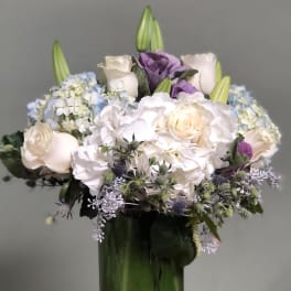 Bouquet of white and lavender flowers in a tall glass vase