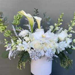 White floral arrangement in a white vase with calla lilies and roses