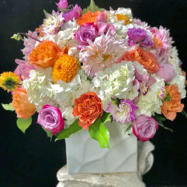 Colorful bouquet of roses, hydrangeas, and daisies in a white vase