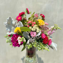 Mixed bouquet in a glass vase with bright pink, yellow, and white flowers