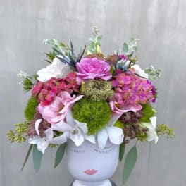 Pink and white floral arrangement in a white face vase