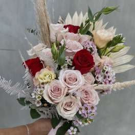 Hand-tied bouquet of pink and red roses with dried grasses