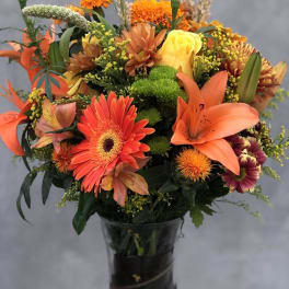 Orange and yellow mixed bouquet in a dark glass vase