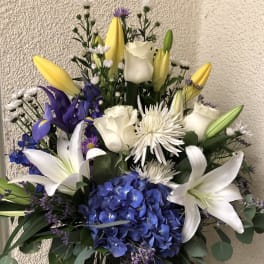 Bouquet of white lilies, roses, blue hydrangea, and yellow tulips