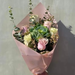 Pink-wrapped bouquet with roses and green ornamental cabbage