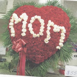 Heart-shaped red floral arrangement with white rose lettering and a red ribbon bow