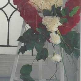 Heart-shaped floral wreath of red and white carnations on a stand