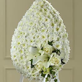 White funeral spray with lilies and roses on a standing easel