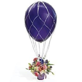 Flower arrangement with a purple balloon attached above it