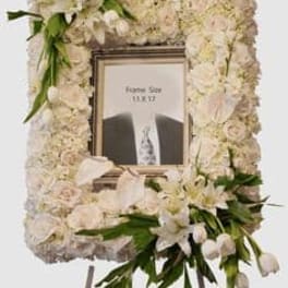White floral funeral frame with a central photo opening