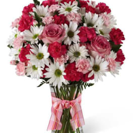 Pink and white mixed bouquet in a clear glass vase with a pink ribbon