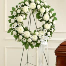 White floral wreath on a stand with a white ribbon