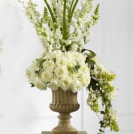 Tall white floral arrangement in a decorative urn on a pedestal