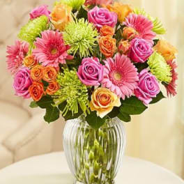 Colorful bouquet of roses and gerbera daisies in a clear glass vase
