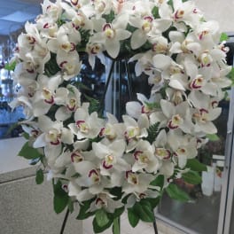 Large white orchid wreath on a black stand
