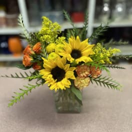 Sunflower bouquet with orange roses in a glass vase