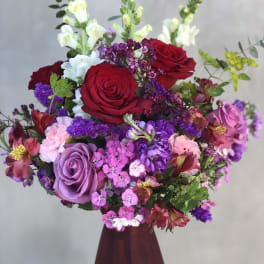 Bouquet of red, purple, and pink flowers in a burgundy vase