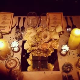 Cream floral centerpiece on a candlelit dining table