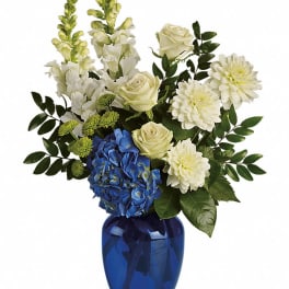 Blue vase with white flowers, blue hydrangea, and greenery
