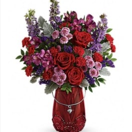 Red and purple mixed flower arrangement in a red vase