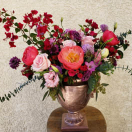 Large mixed bouquet in a metallic urn vase with pink and red blooms