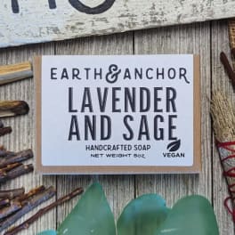 Bar of lavender and sage handcrafted soap on rustic wood with dried sticks and sea glass