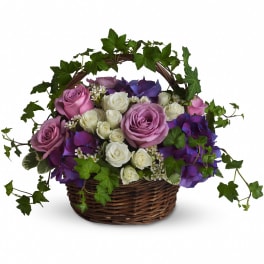 Pink and white roses in a wicker basket with purple hydrangeas and ivy