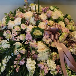 Large pastel floral arrangement with roses, daisies, and a satin ribbon