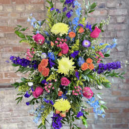 Tall mixed flower arrangement with pink roses, yellow mums, and blue-purple blooms