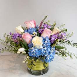 Pink and white roses with blue hydrangeas in a glass vase