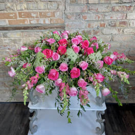 Large pink rose arrangement with trailing greenery on a white pedestal