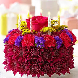 Round floral cake with candles and a red rose on top