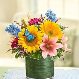 Sunflowers and pink lilies in a green glass vase
