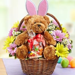 Teddy bear in a wicker basket with pastel flowers and bunny ears