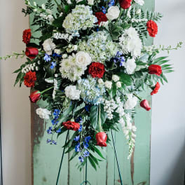 Large standing floral spray with red, white, and blue flowers on an easel.