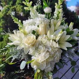 White floral bouquet in a clear glass vase with tall blooms and round greenery