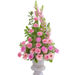 Tall pink arrangement with roses, carnations, gerbera daisies, and snapdragons in a pale pedestal vase