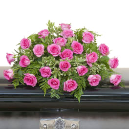 Pink rose casket spray arranged on a dark metal casket