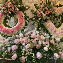 Pink and white floral wreaths and bouquets arranged on stands