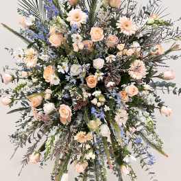Large standing floral spray with peach roses and blue delphinium