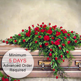 Red rose casket spray draping over a closed bronze casket