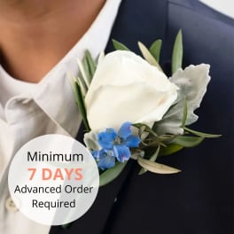 White rose and blue flower boutonniere pinned to a navy suit lapel