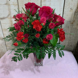 Red roses and carnations arranged in a clear glass vase