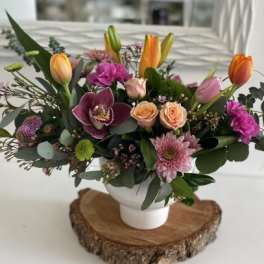 Mixed bouquet with tulips, roses, orchids, and chrysanthemums in a white vase