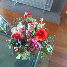 Mixed bouquet with red, pink, and purple flowers in a glass vase