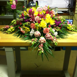 Large mixed floral arrangement with roses, lilies, and bright yellow blooms