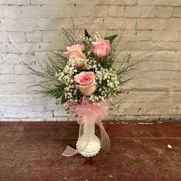 Pink roses in a white vase with a pink ribbon
