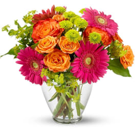 Bouquet of pink gerbera daisies and orange roses in a clear glass vase